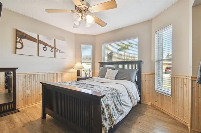 bedroom with hardwood / wood-style floors, ceiling fan, and wood walls