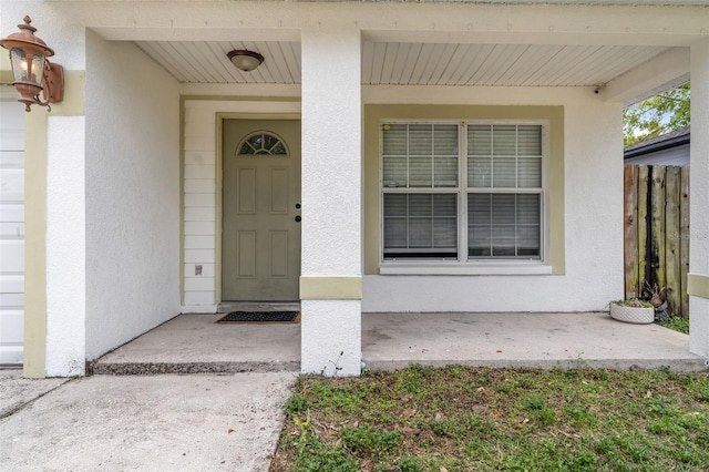 property entrance with fence, covered porch, and stucco siding