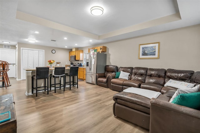 living area featuring visible vents, recessed lighting, a raised ceiling, and light wood-style floors