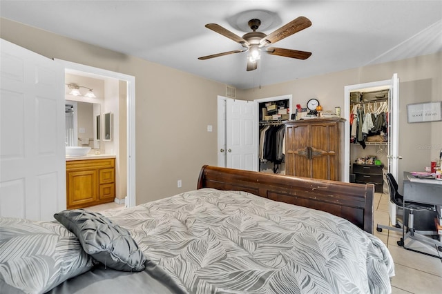 bedroom featuring a spacious closet, visible vents, connected bathroom, light tile patterned floors, and a ceiling fan