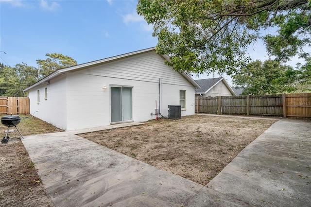 rear view of property with cooling unit, a fenced backyard, and a patio area