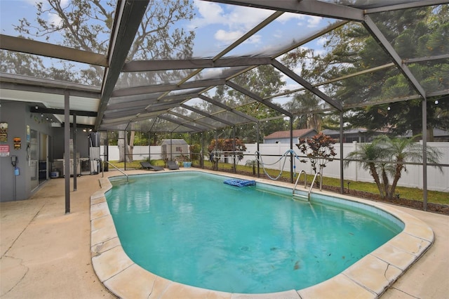 view of pool with glass enclosure and a patio area