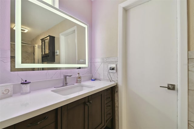 bathroom with vanity, a shower with door, and tile walls