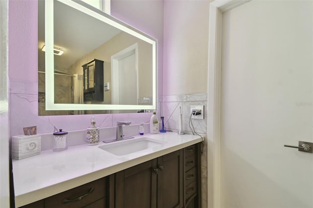 bathroom with vanity, a shower with shower door, and tile walls