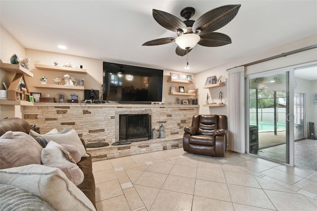 tiled living room with ceiling fan and a fireplace