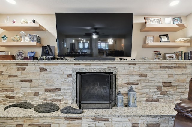 interior details featuring a fireplace and ceiling fan