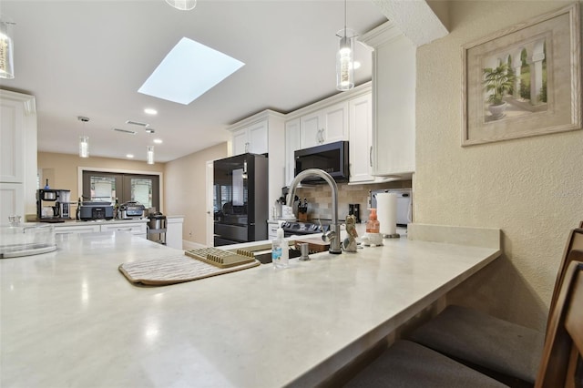 kitchen with white cabinetry, hanging light fixtures, a skylight, fridge, and kitchen peninsula