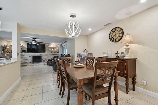 dining area with a fireplace, ceiling fan with notable chandelier, and light tile patterned floors