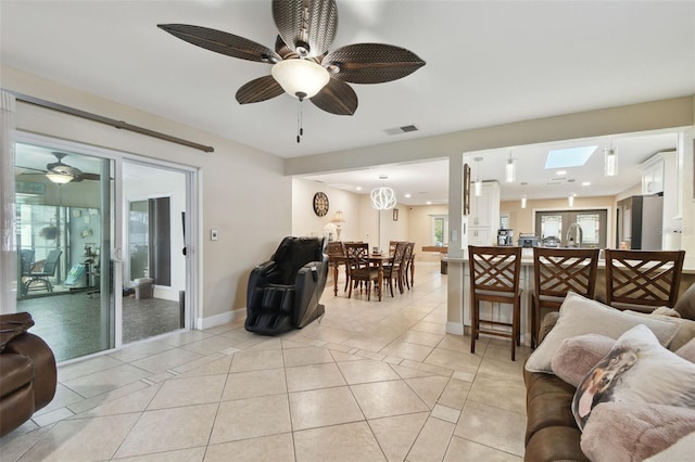 tiled living room featuring sink, a skylight, and ceiling fan