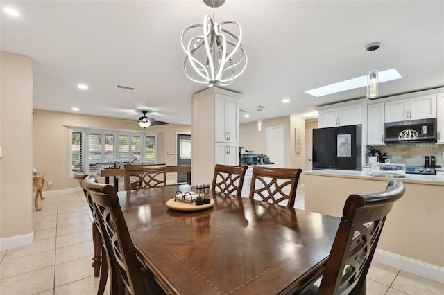 tiled dining space with ceiling fan, a skylight, and decorative columns