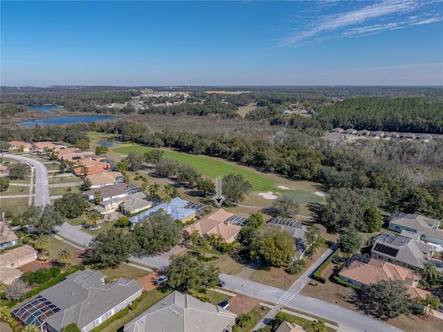 drone / aerial view featuring golf course view, a water view, a wooded view, and a residential view