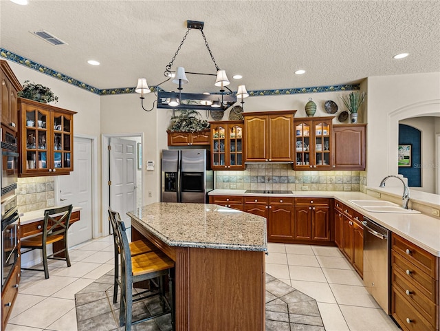 kitchen with a breakfast bar, light tile patterned floors, visible vents, a sink, and black appliances