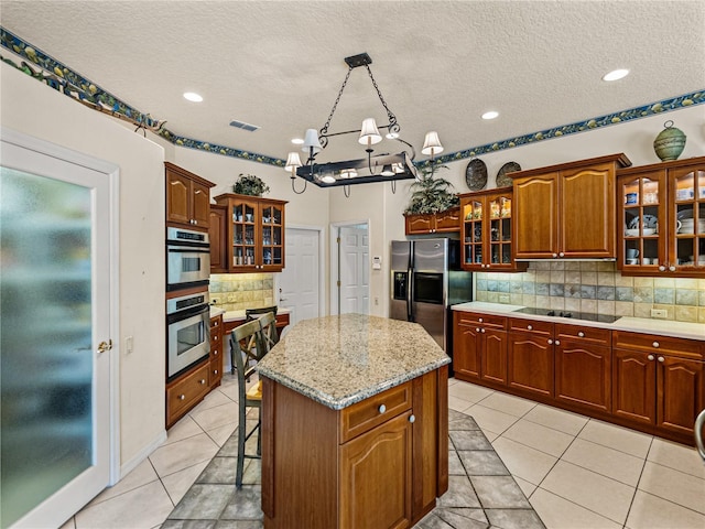 kitchen with stainless steel appliances, light tile patterned flooring, a kitchen island, and a kitchen breakfast bar