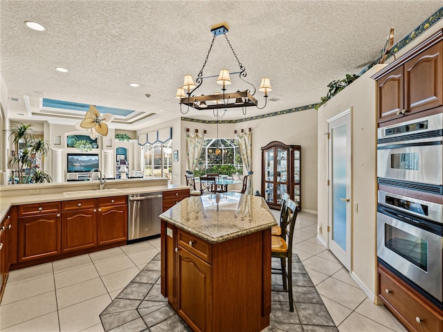 kitchen featuring a breakfast bar area, light tile patterned floors, appliances with stainless steel finishes, a kitchen island, and a sink