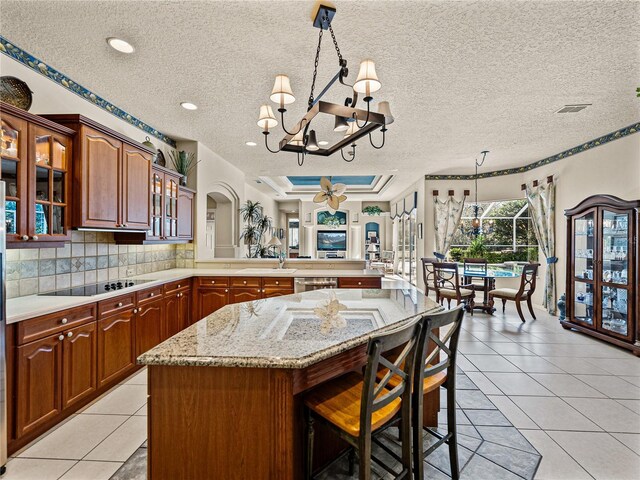 kitchen with a peninsula, light tile patterned floors, black electric stovetop, and glass insert cabinets