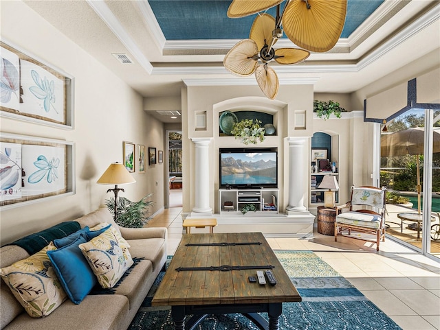 tiled living area with a tray ceiling, visible vents, ornamental molding, ceiling fan, and ornate columns