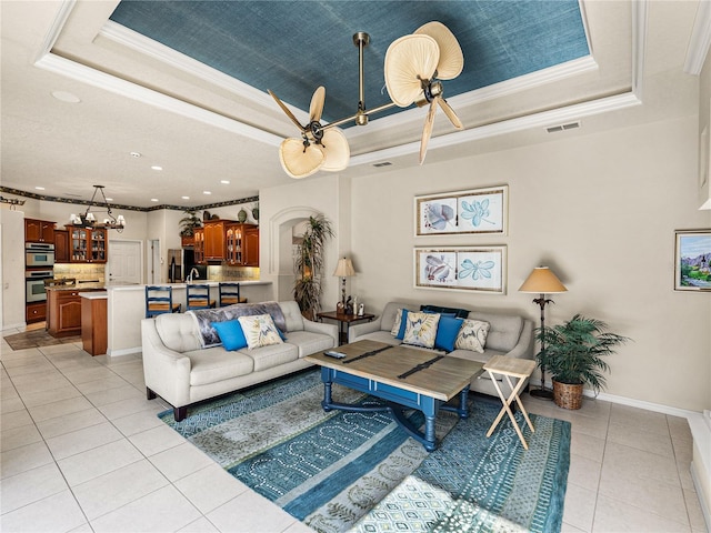 living area featuring light tile patterned floors, baseboards, a tray ceiling, and crown molding