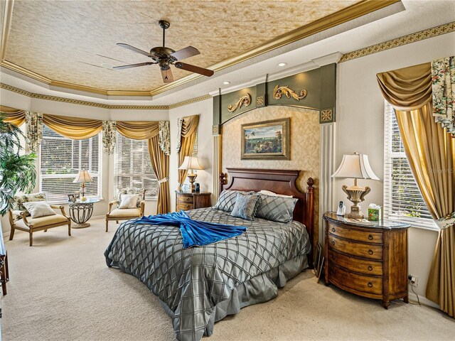 bedroom featuring ornamental molding, carpet floors, a tray ceiling, and multiple windows