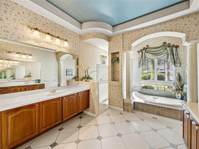 bathroom featuring a walk in shower, vanity, ornate columns, and wallpapered walls