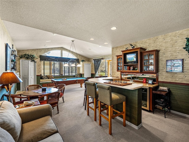 dining room with lofted ceiling, a wainscoted wall, light carpet, and a textured ceiling