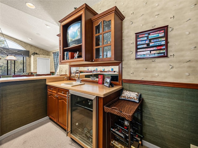 bar with beverage cooler, light colored carpet, lofted ceiling, a textured ceiling, and a sink