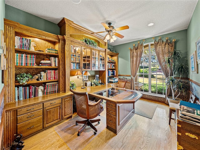 office space with light wood-type flooring, ceiling fan, and a textured ceiling