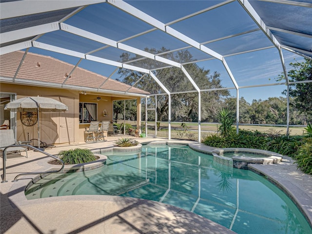 view of swimming pool featuring glass enclosure, a pool with connected hot tub, ceiling fan, and a patio