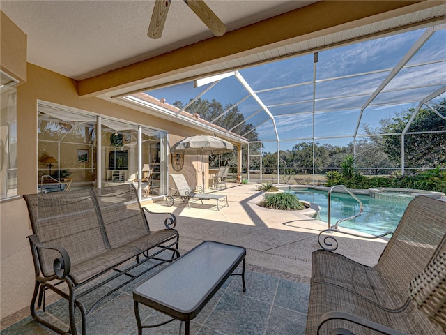 view of pool with glass enclosure, a pool with connected hot tub, ceiling fan, and a patio area