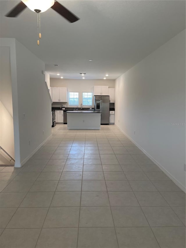 unfurnished living room with light tile patterned flooring, sink, and ceiling fan