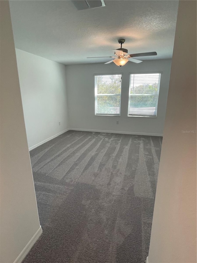 unfurnished room featuring ceiling fan, dark carpet, and a textured ceiling