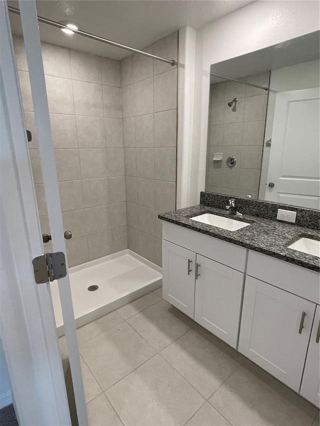 bathroom with tiled shower, vanity, and tile patterned flooring