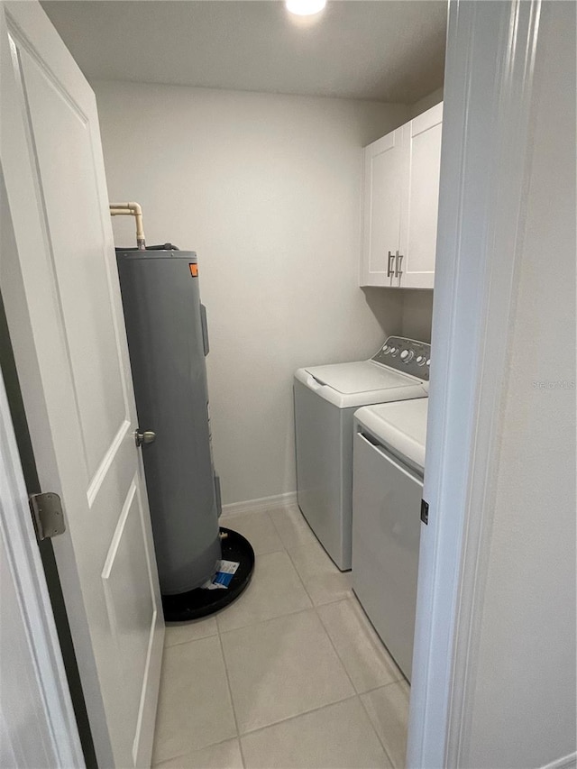 washroom with cabinets, electric water heater, light tile patterned floors, and washer and clothes dryer