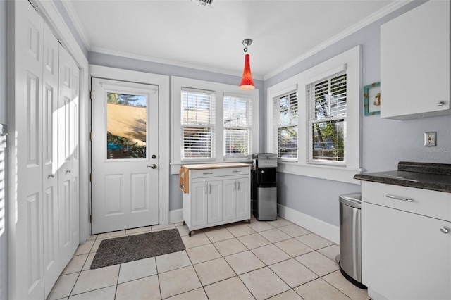 kitchen featuring hanging light fixtures, ornamental molding, light tile patterned flooring, and white cabinets