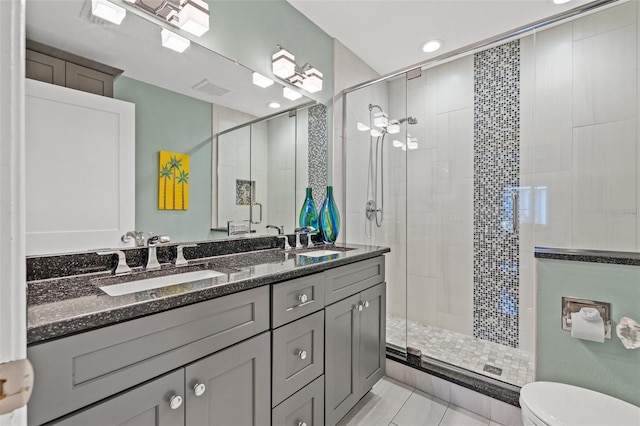 bathroom featuring vanity, a shower with door, and toilet