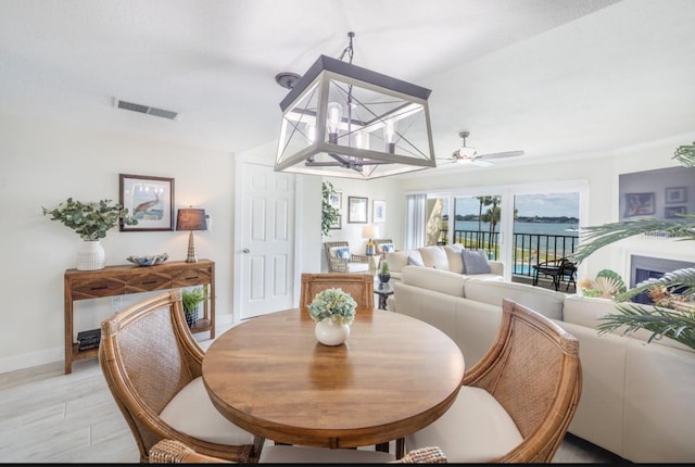 dining space with ceiling fan with notable chandelier and light hardwood / wood-style flooring