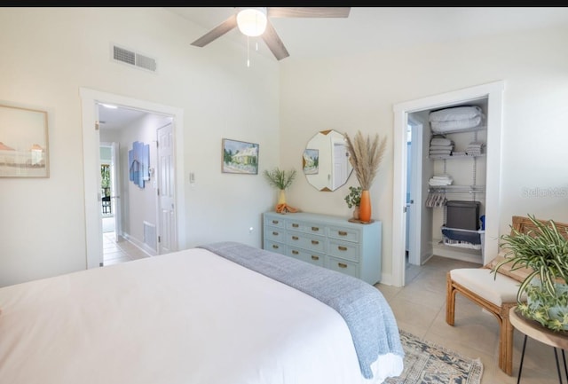 tiled bedroom featuring ceiling fan and a spacious closet