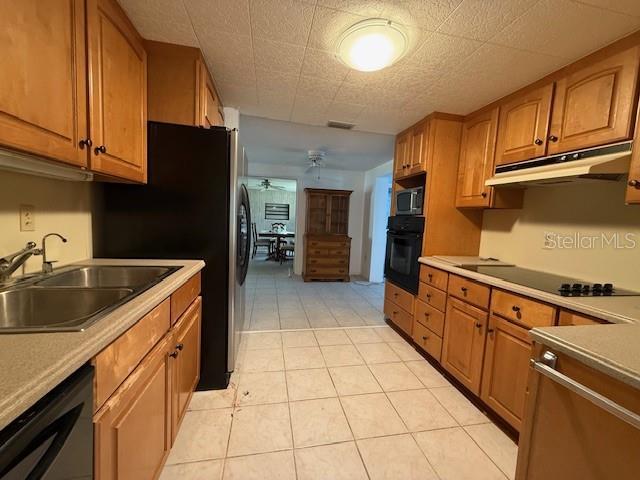 kitchen with light tile patterned flooring, ceiling fan, sink, and black appliances