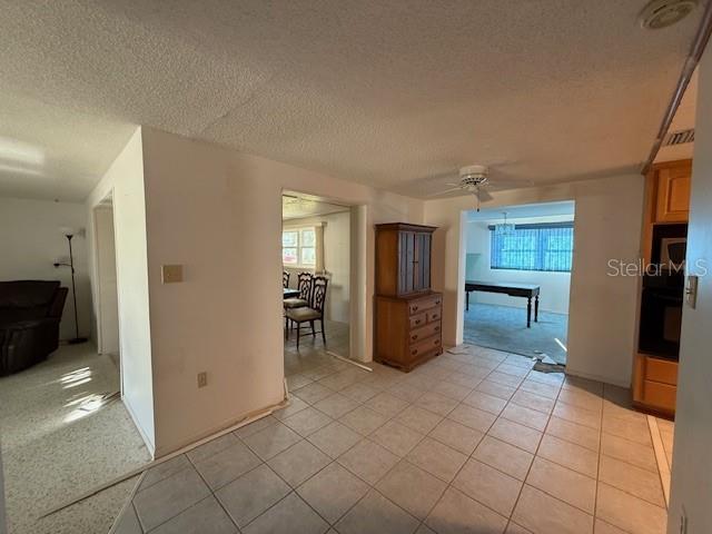 interior space featuring ceiling fan, oven, light carpet, and a textured ceiling