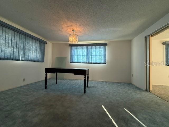 unfurnished office featuring dark carpet and a textured ceiling