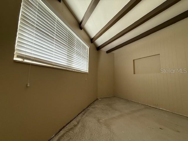 empty room featuring lofted ceiling with beams