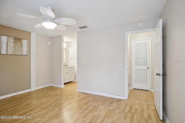 unfurnished bedroom with ceiling fan, connected bathroom, a textured ceiling, and light hardwood / wood-style flooring