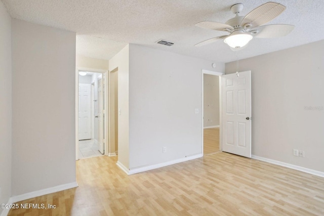 empty room with ceiling fan, a textured ceiling, and light hardwood / wood-style flooring