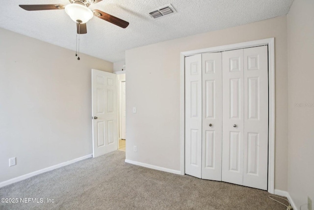 unfurnished bedroom with ceiling fan, light colored carpet, a textured ceiling, and a closet