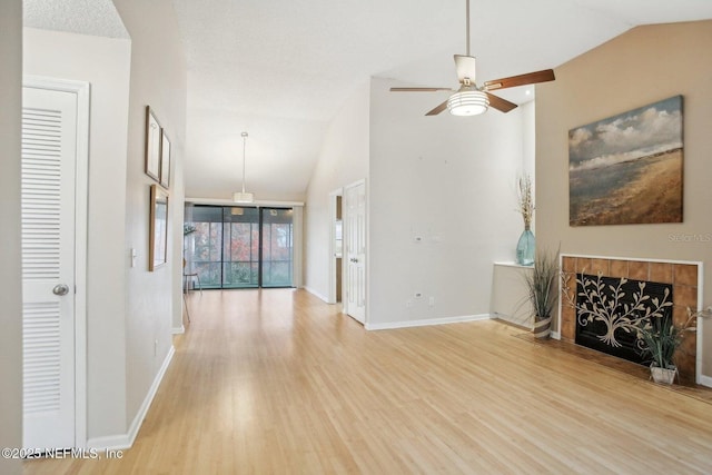 unfurnished living room with a tiled fireplace, light hardwood / wood-style flooring, high vaulted ceiling, and ceiling fan