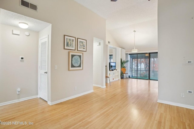 unfurnished living room featuring vaulted ceiling, light hardwood / wood-style flooring, and a textured ceiling