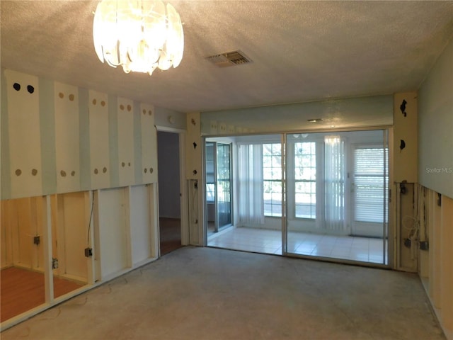 empty room featuring a textured ceiling and a notable chandelier