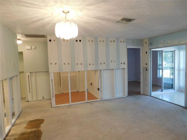 empty room featuring a textured ceiling and a notable chandelier