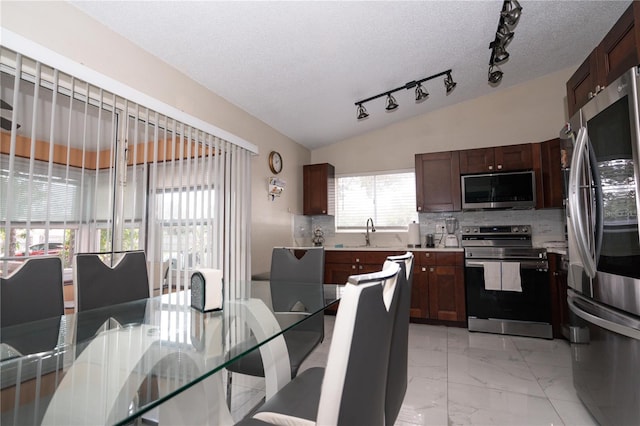 kitchen featuring vaulted ceiling, appliances with stainless steel finishes, sink, backsplash, and a textured ceiling