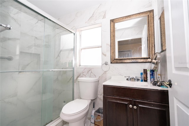 bathroom with tile walls, vanity, a shower with door, and toilet