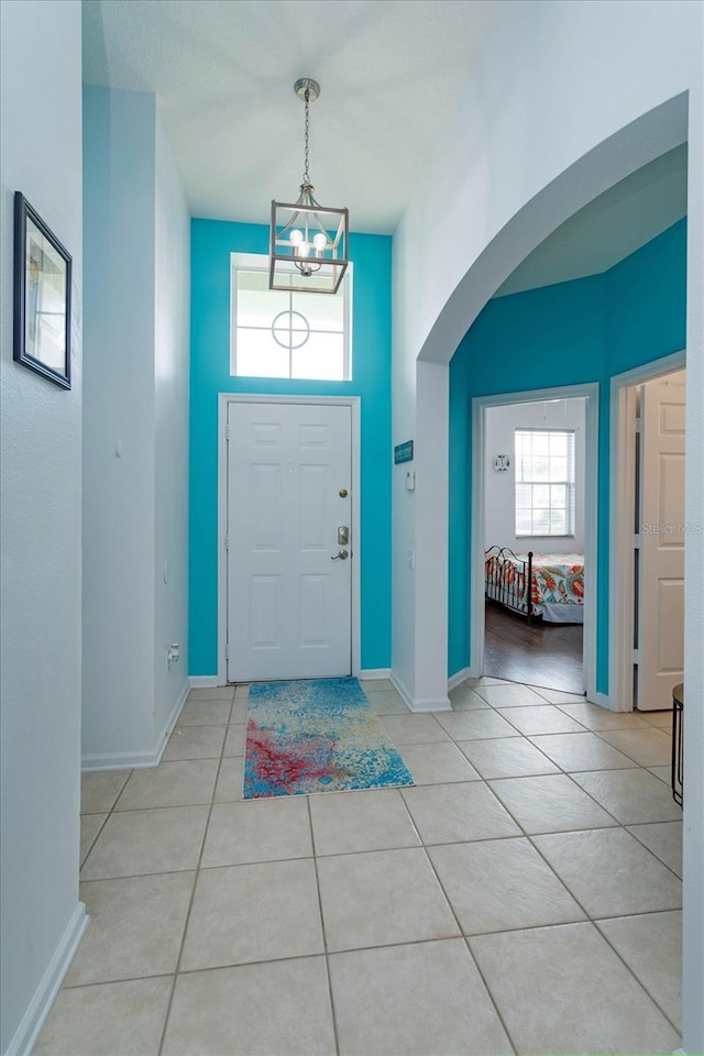 foyer entrance with a chandelier, light tile patterned floors, and a high ceiling